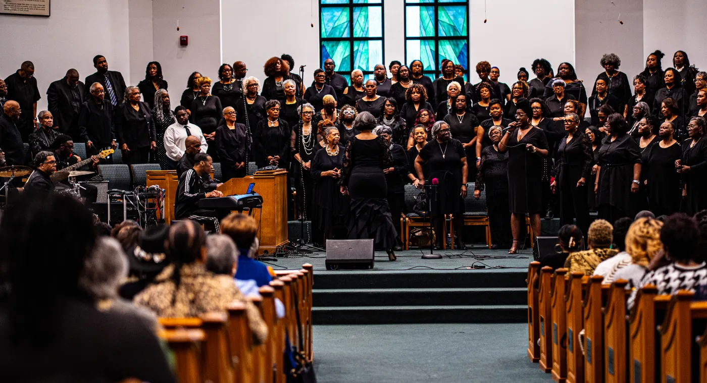 Gospel singer performing with microphone under stage lighting — placeholder