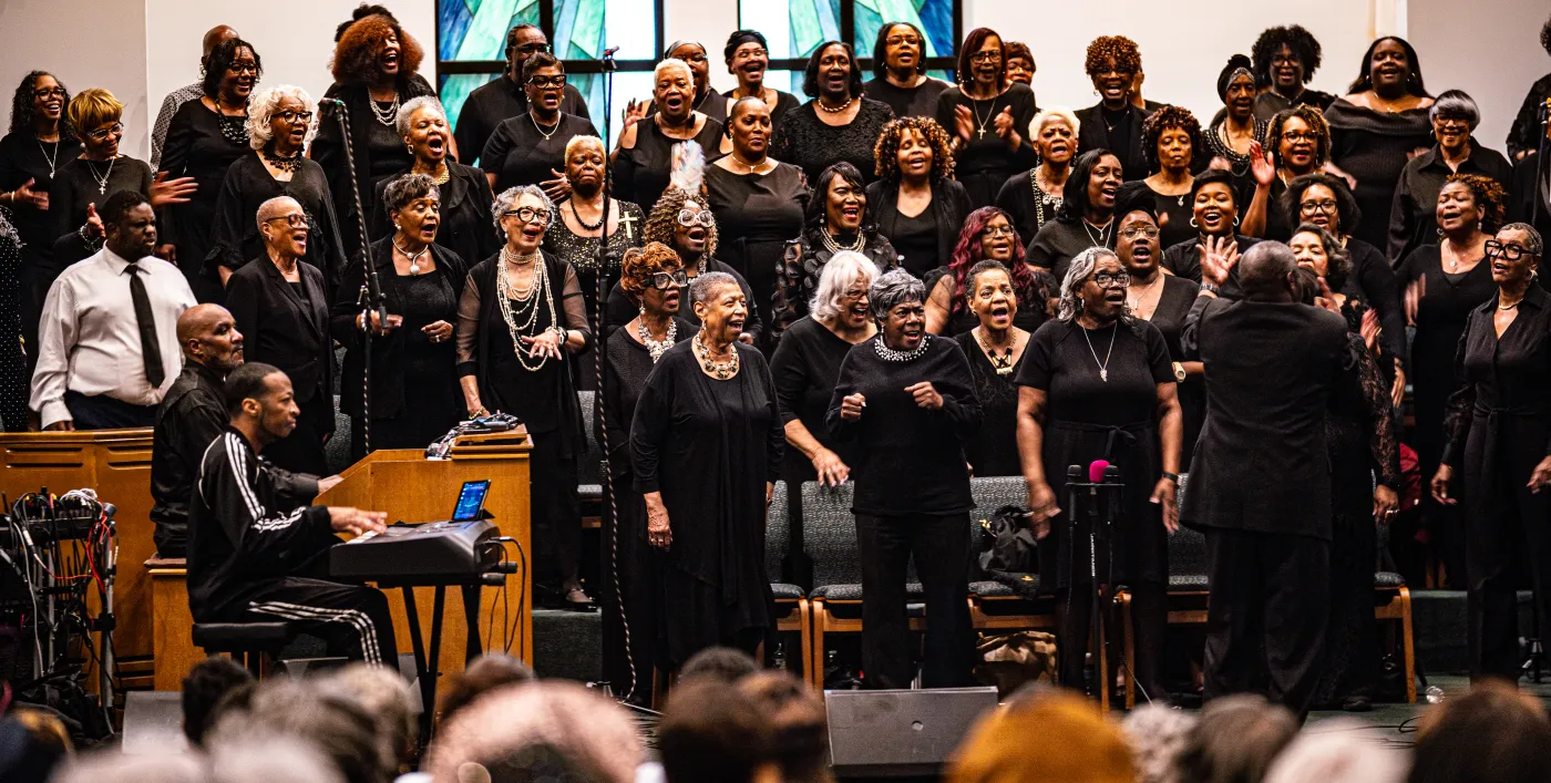 Gospel singer performing with microphone under stage lighting — placeholder