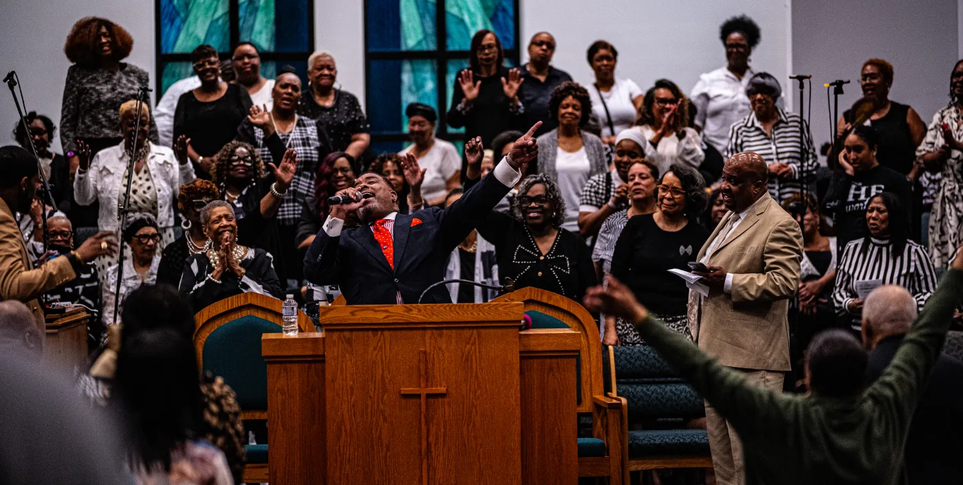 Gospel singer performing with microphone under stage lighting — placeholder